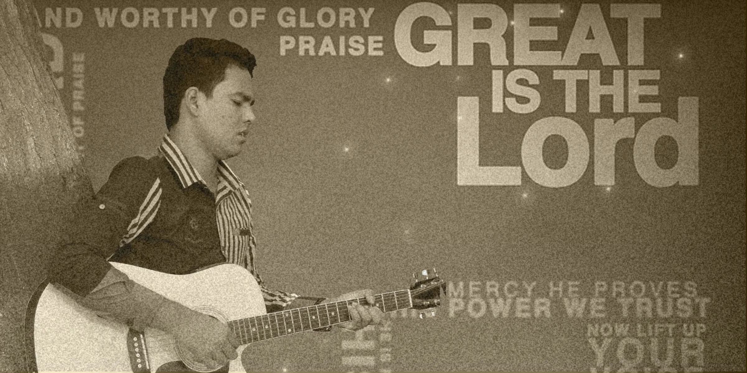 Ricky Biswasi playing a Korg keyboard during a service, with the congregation and a lit cross behind him